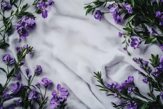 Фиолетовые цветы и зелёные веточки на мятой светлой ткани