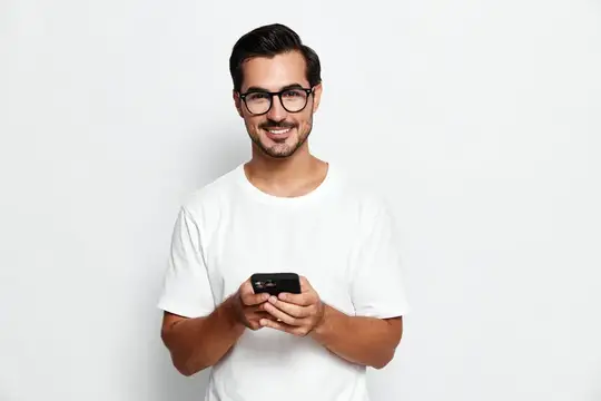 Улыбающийся мужчина в очках и белой футболке держит смартфон