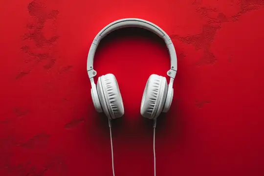 Белые наушники лежат на ярко-красном фоне