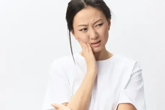 Азиатская девушка с болью в зубе держится за щёку