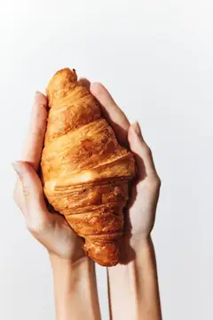 Руки держат свежий круассан на светлом фоне