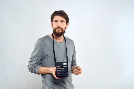 Фотограф-мужчина с профессиональной камерой, работа, студийные технологии, современное искусство на светлом фоне