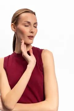 Молодая женщина с закрытыми глазами касается щеки рукой