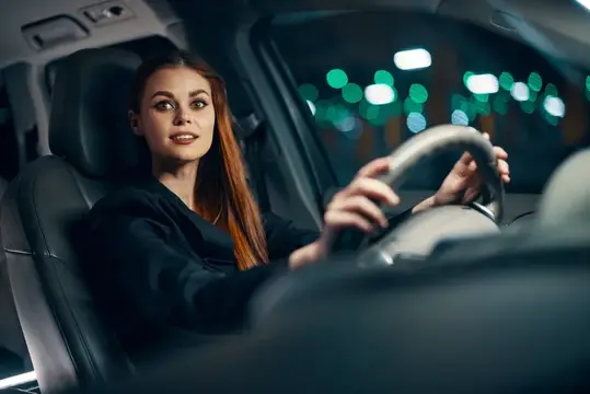 Рыжеволосая девушка за рулём автомобиля ночью
