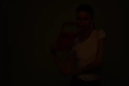 Молодая женщина в белой футболке в темноте
