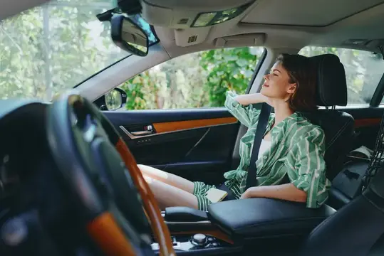 Молодая женщина с закрытыми глазами отдыхает на пассажирском сиденье автомобиля