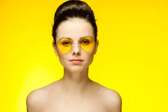 Симпатичная женщина в жёлтых очках с обнажёнными плечами веселится