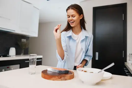Улыбающаяся девушка готовит завтрак на светлой кухне
