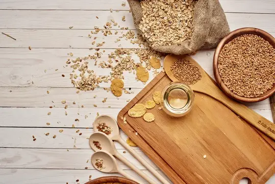Овсяные хлопья, зерна и масло на светлом деревянном столе