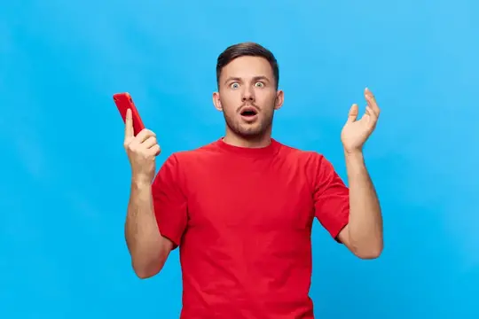 Удивлённый мужчина в красной футболке с телефоном на синем фоне