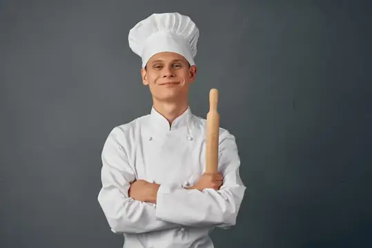 Повар держит скалку в руках, демонстрируя профессионализм в кулинарии