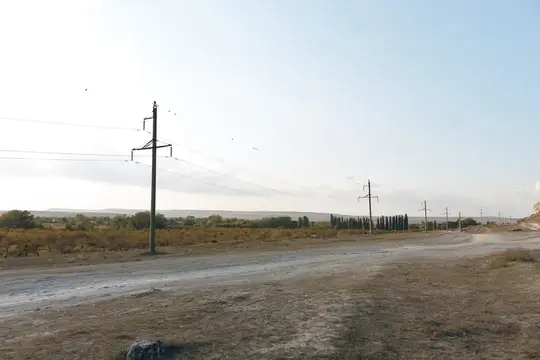 Пустая грунтовая дорога уходит к горизонту под высоким небом