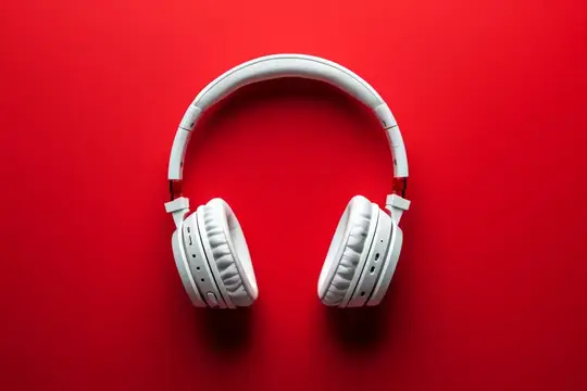 Белые наушники на ярко-красном фоне с местом для текста, музыкальная концепция для рекламы и маркетинга