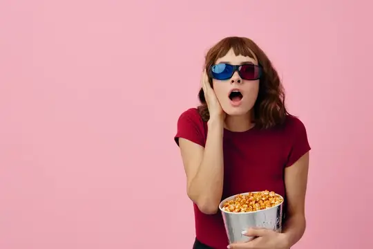 Девушка в 3D-очках с попкорном удивлённо смотрит кино на розовом фоне