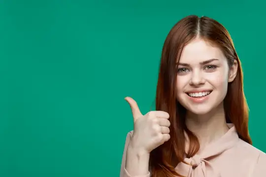 Улыбающаяся рыжеволосая девушка показывает большой палец вверх на зелёном фоне