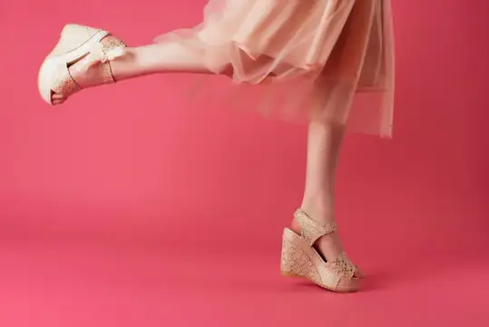 Женские ноги в бежевых туфлях на розовом фоне