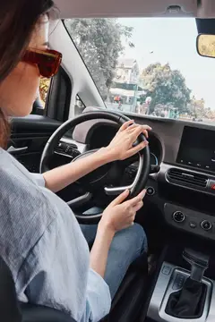 Женщина в солнцезащитных очках за рулём автомобиля