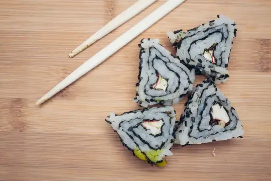 Роллы с лососем и палочки на бамбуковой доске
