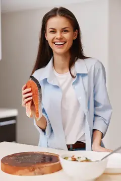 Счастливая женщина готовит свежее филе лосося на кухне для вкусного обеда