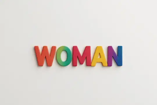 Разноцветные деревянные буквы складываются в слово WOMAN на белом фоне
