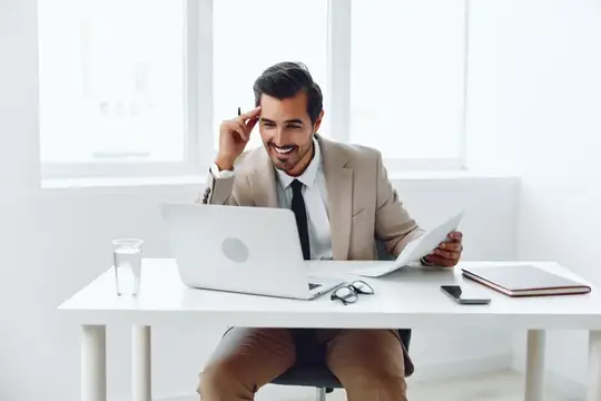 Улыбающийся мужчина в костюме работает за ноутбуком в светлом офисе