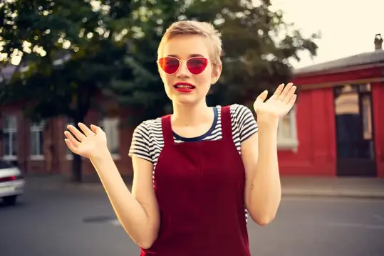 Симпатичная женщина в солнцезащитных очках позирует на открытом воздухе, демонстрируя стиль жизни и модный образ