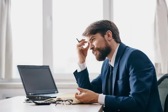Бизнесмены работают за ноутбуком в офисе, на их лицах эмоции недовольства