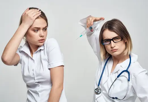 Строгая женщина-врач с шприцем и испуганная пациентка в белом халате
