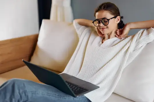 Счастливая женщина работает за ноутбуком в уютном домашнем офисе, наслаждаясь образом жизни фрилансера и успехом стартапа