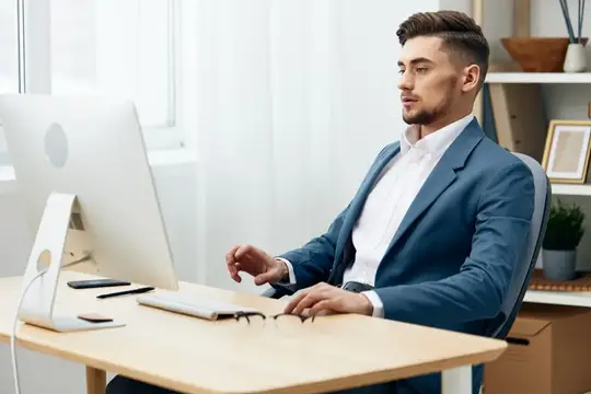 Менеджер в очках работает за компьютером в офисе, используя современные технологии