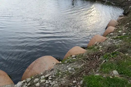 Бетонные полусферы вдоль заросшего травой берега водоёма