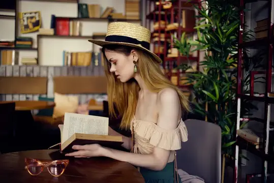 Симпатичная женщина читает книгу в кафе