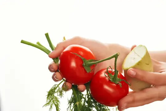 Женские руки держат спелые помидоры и половинку картофеля