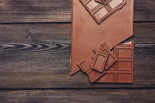 Сладкая шоколадная плитка на деревянном фоне и конфеты, текстурный снимок