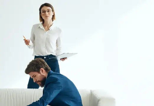 Коллеги по работе общаются в финансовом офисе, сидя на белом диване