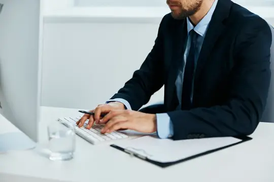 Мужчина в костюме работает за компьютером в офисе