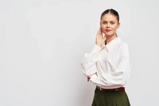 Уверенная молодая женщина в белой рубашке на сером фоне