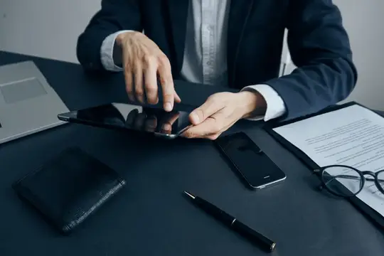Мужчина в деловом костюме работает с планшетом за столом с документами