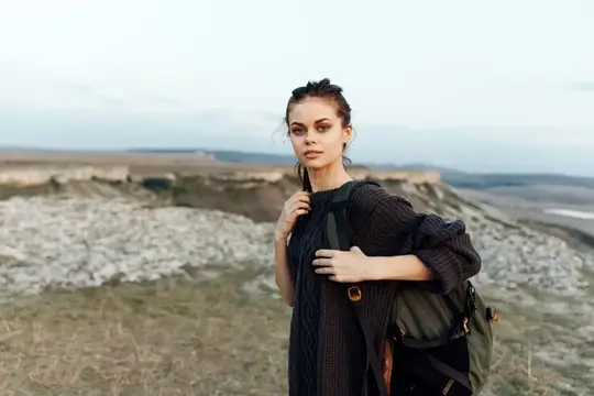 Молодая женщина с рюкзаком на фоне скалистого пейзажа