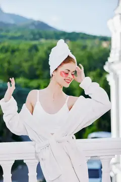 Улыбающаяся девушка в белом халате и розовых очках на балконе