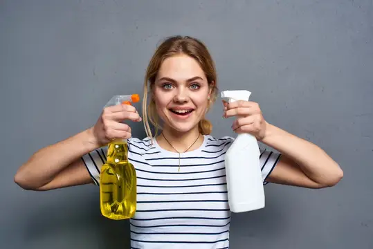 Улыбающаяся блондинка с чистящими средствами в руках