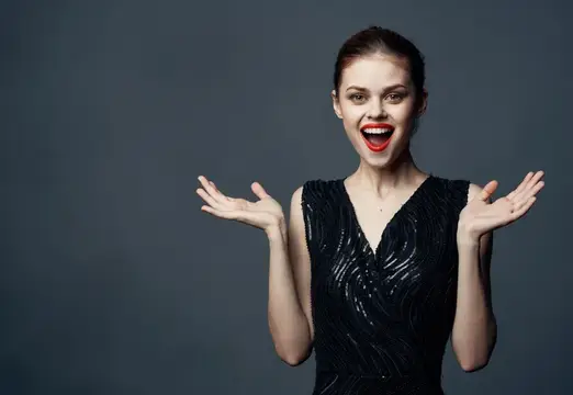 Привлекательная женщина жестикулирует руками на сером фоне