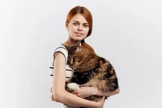 Рыжеволосая девушка держит на руках пушистую черепаховую кошку