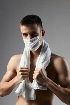 Молодой спортивный мужчина с полотенцем на шее и защитной маской
