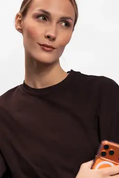 Портрет молодой женщины в темном топе, держащей смартфон и смотрящей в сторону