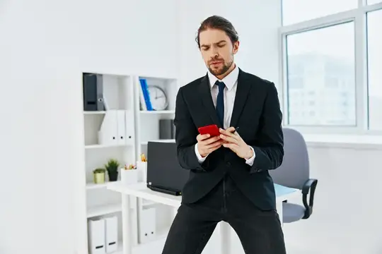 Бизнесмен держит телефон в офисе