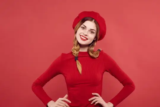 Улыбчивая девушка с косичками в красном берете на красном фоне
