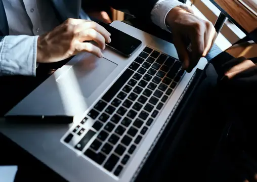 Мужские руки печатают на ноутбуке за рабочим столом