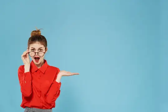Удивлённая девушка в очках и красной рубашке на голубом фоне