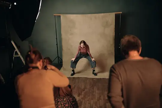 Девушка в брюках в клетку позирует фотографам в студии